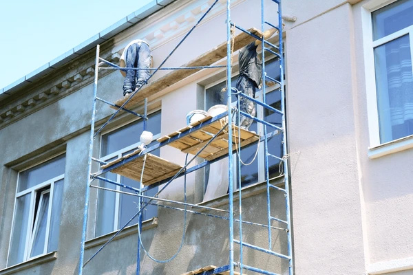 Équipe de peintres façadiers travaillant sur un échafaudage pour le ravalement technique et la peinture d'un immeuble